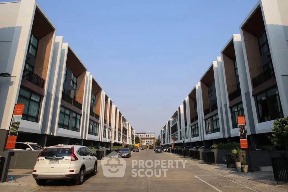 Modern townhouse complex with sleek design and ample parking space, showcasing contemporary urban living.