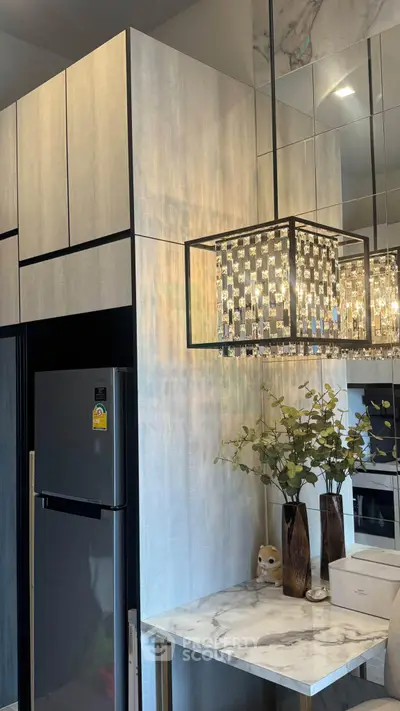 Modern kitchen with sleek cabinetry, marble countertop, and elegant chandelier lighting.
