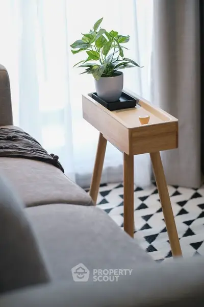 Stylish modern living room with cozy sofa and elegant side table featuring a potted plant, perfect for relaxation.