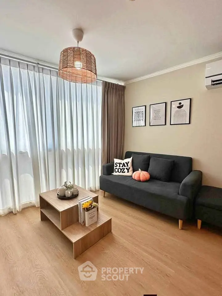 Cozy living room with modern decor, featuring a black sofa, stylish coffee table, and elegant lighting.