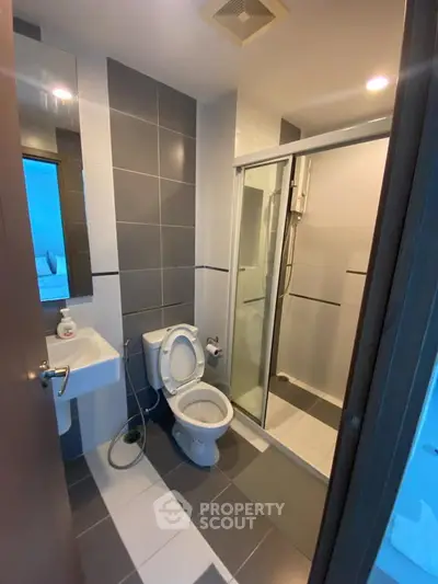 Modern bathroom with sleek design, featuring a glass shower enclosure and stylish tile work.