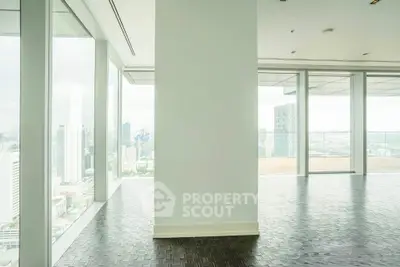 Spacious modern living room with floor-to-ceiling windows offering stunning city views.
