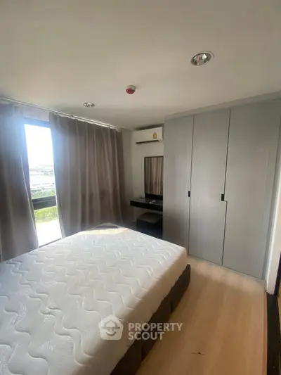 Modern bedroom with large window, built-in wardrobe, and sleek wooden flooring.