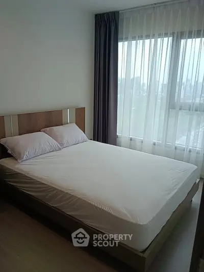 Modern bedroom with large window and natural light in a stylish apartment.