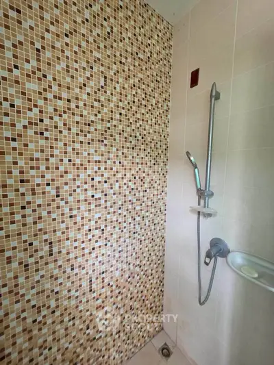 Modern bathroom with mosaic tile wall and sleek shower fixture
