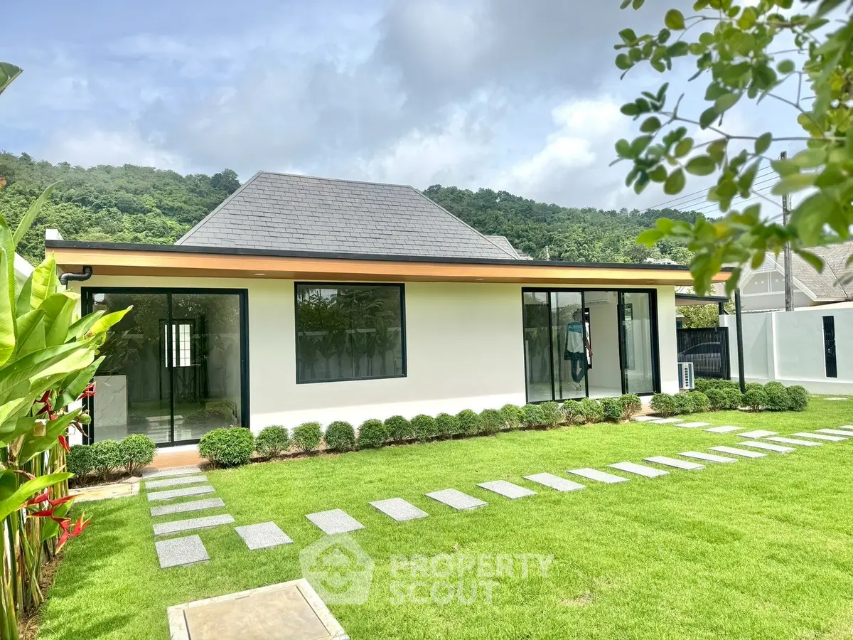 Stunning modern house with lush green lawn and scenic mountain backdrop, perfect for serene living.