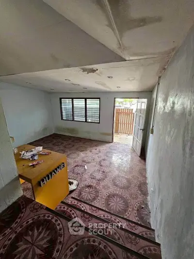 Spacious room with unique patterned flooring and open doorway leading to a bright outdoor area.