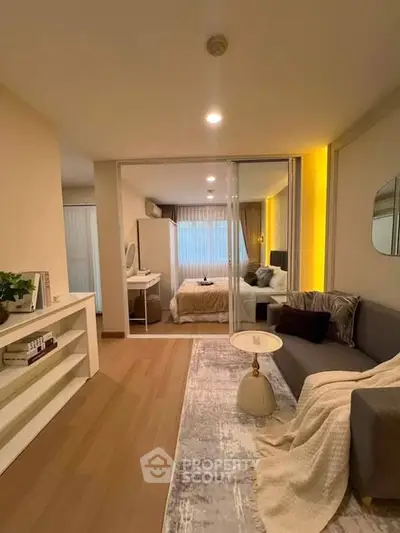 Modern living room with cozy decor and view into stylish bedroom, featuring elegant lighting and contemporary furniture.