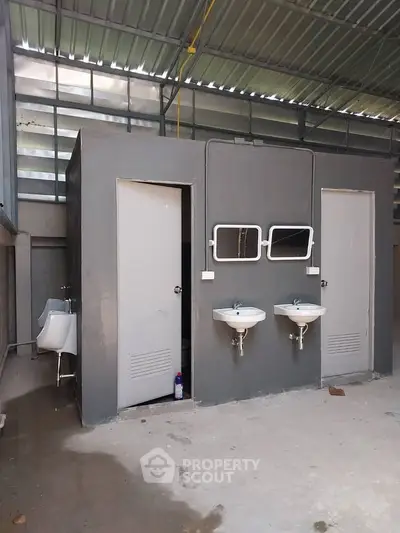 Industrial-style shared bathroom with sinks and urinals in a modern building.