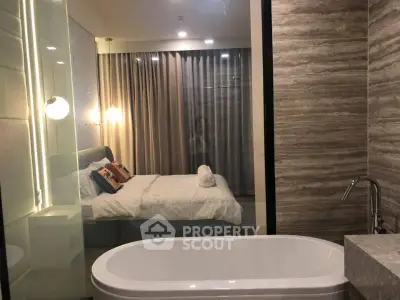 Luxurious bedroom with ensuite bathroom featuring a modern bathtub and elegant lighting.