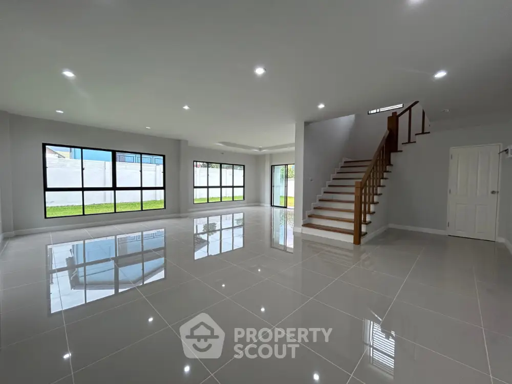 Spacious modern living room with glossy tile flooring and elegant staircase