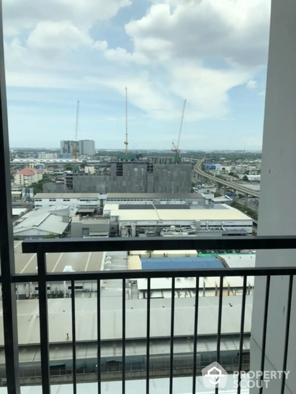 Stunning cityscape view from high-rise balcony with construction cranes and skyline