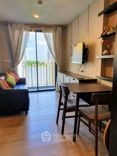 Modern living room with balcony and river view, featuring sleek furniture and natural light.