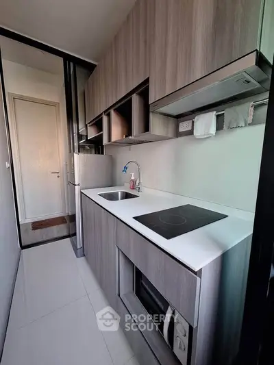 Modern compact kitchen with sleek cabinetry and built-in appliances in a stylish apartment.