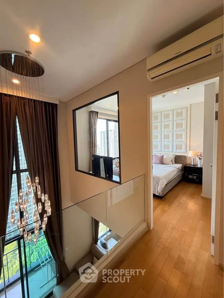 Luxurious modern bedroom with elegant lighting and city view, featuring hardwood floors and stylish decor.