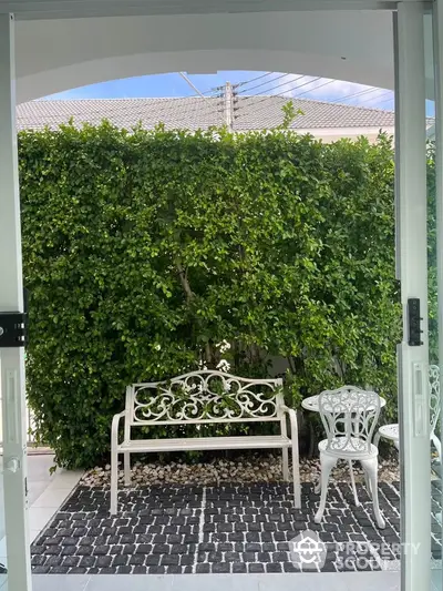 Charming garden patio with elegant white furniture and lush greenery