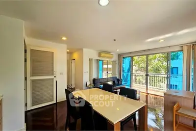 Spacious living room with large windows and balcony access, featuring modern furniture and natural light.