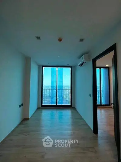 Spacious modern room with large windows offering stunning city views, perfect for urban living.