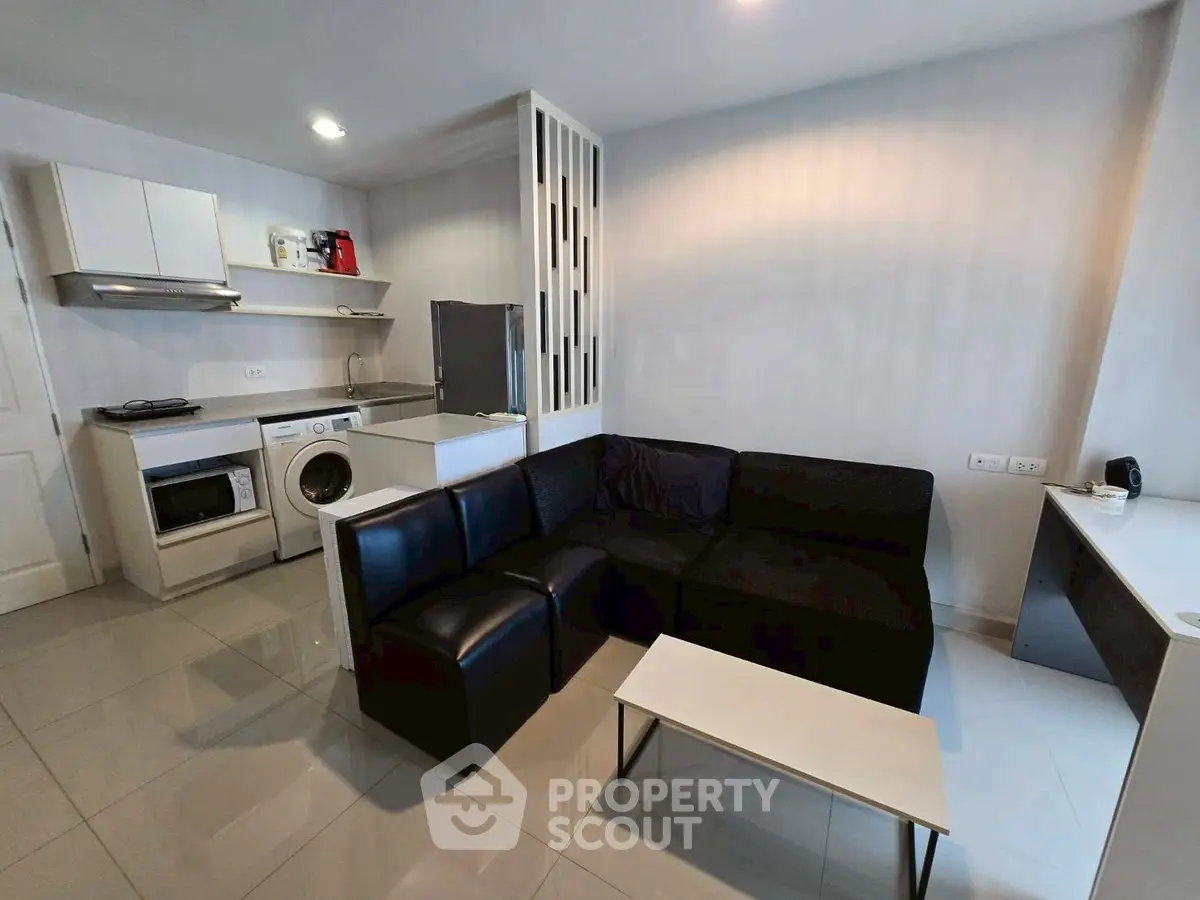 Modern living room with sleek black sofa and integrated kitchen appliances