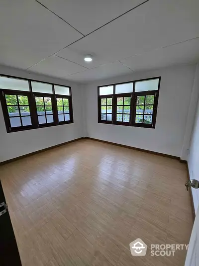 Spacious empty room with large windows and wooden flooring, ideal for customization.