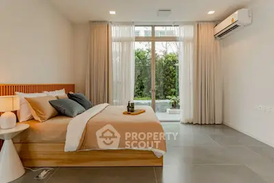 Spacious bedroom with modern decor and garden view, featuring large windows and elegant curtains.