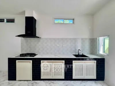 Modern kitchen with sleek black and white design, featuring gas stove and stylish cabinetry.