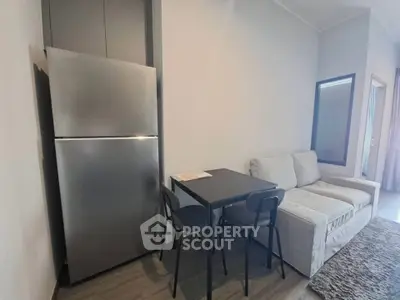 Modern compact living room with cozy sofa, dining table, and sleek refrigerator.