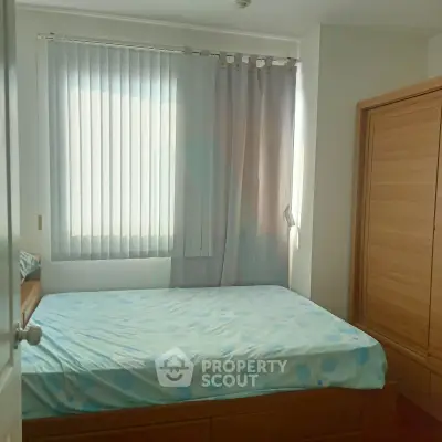 Cozy bedroom with natural light and wooden wardrobe, perfect for relaxation.