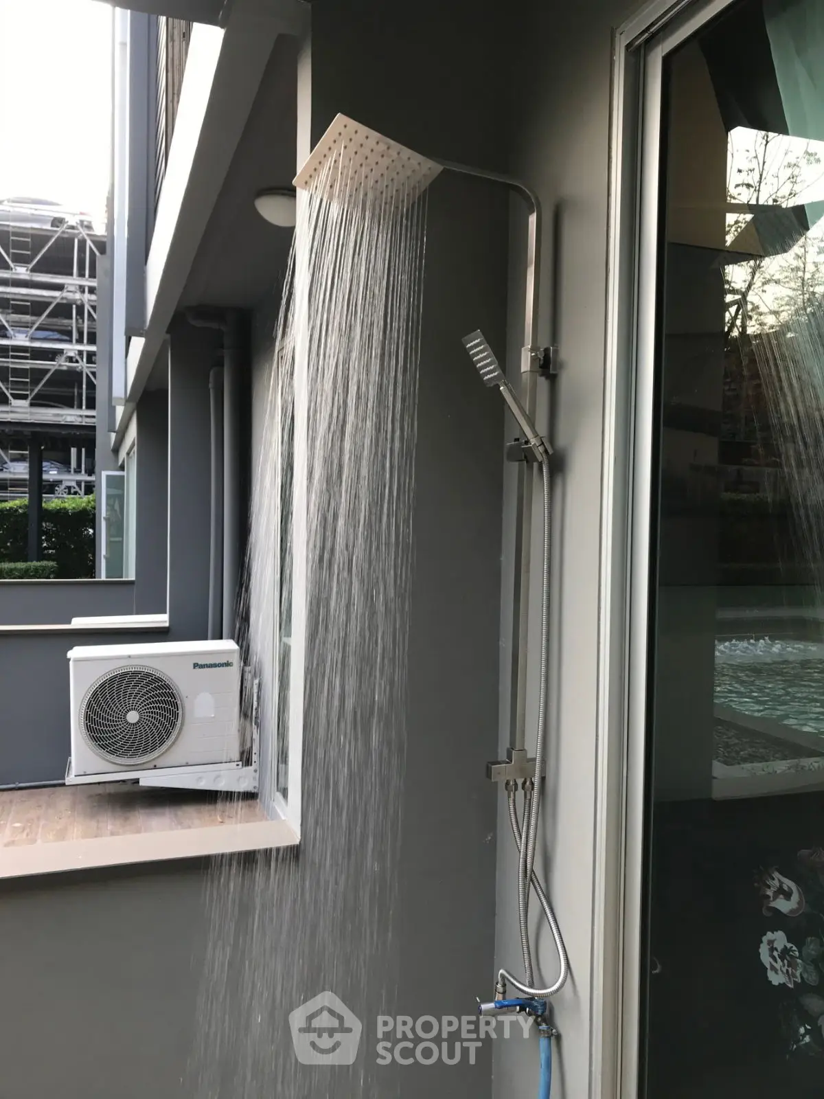 Modern outdoor shower with sleek design and adjacent air conditioning unit.
