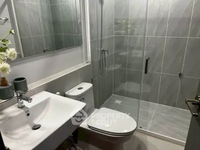 Modern bathroom with sleek design, featuring a glass-enclosed shower and contemporary fixtures.