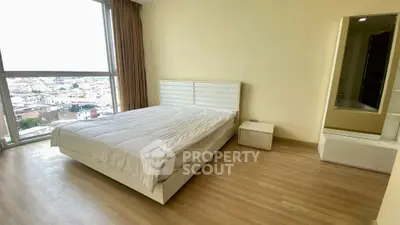 Spacious bedroom with large window offering city views, featuring a modern bed and sleek wooden flooring.
