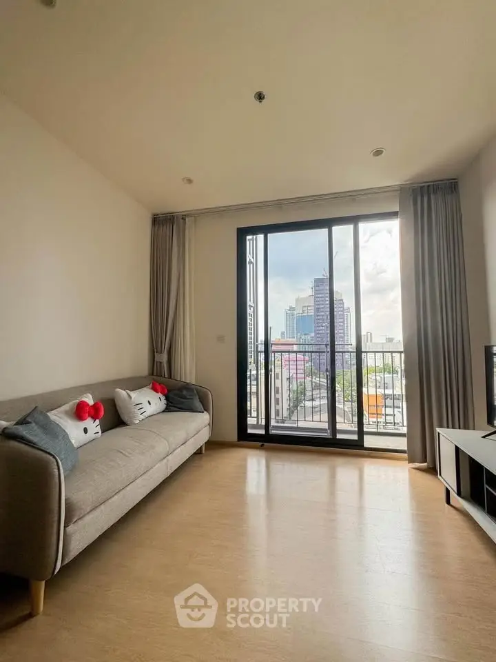 Bright living room with balcony and city view, featuring cozy sofa and modern decor.