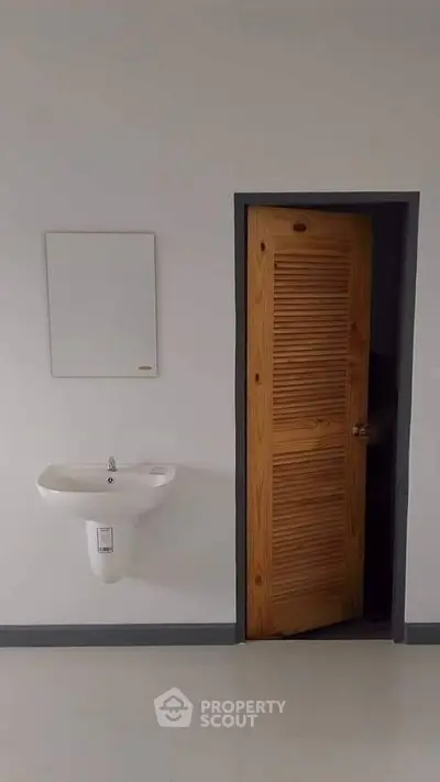 Minimalist bathroom with wooden door and wall-mounted sink