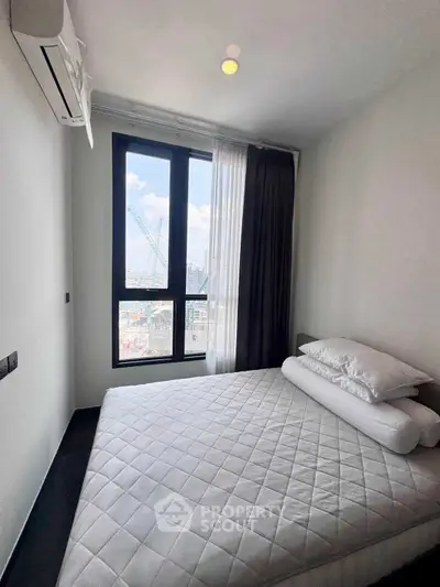Modern bedroom with large window and city view, featuring a comfortable bed and air conditioning.