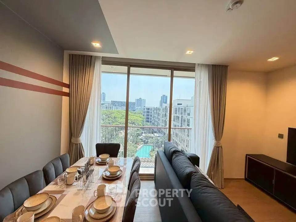 Spacious living room with dining area and city view from large windows in modern apartment.