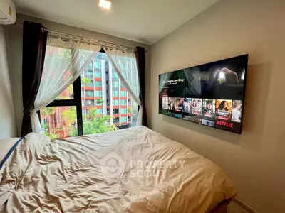 Cozy bedroom with large window and wall-mounted TV, perfect for relaxation.
