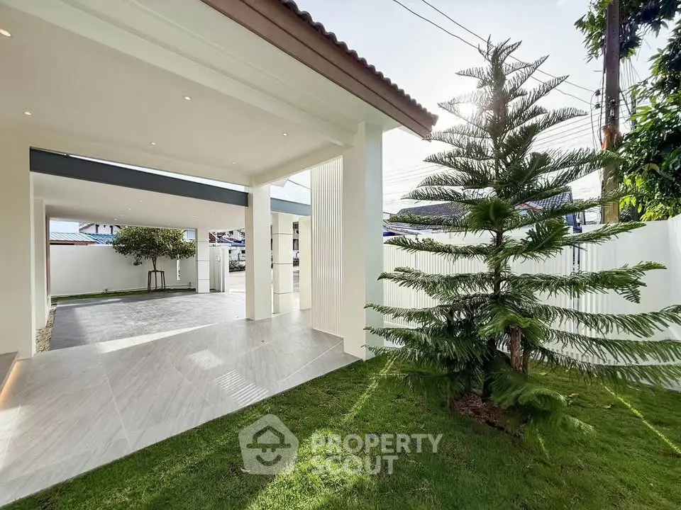 Spacious modern outdoor area with lush greenery and covered patio, perfect for relaxation and entertainment.