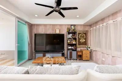 Spacious living room with modern decor and large TV, perfect for relaxation and entertainment.