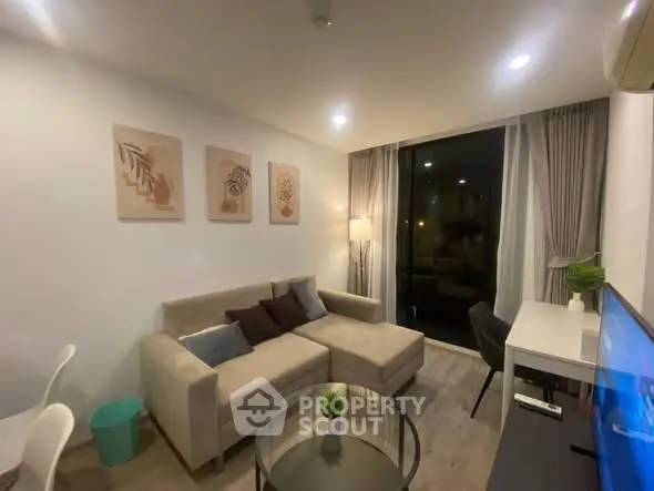 Modern living room with cozy beige sofa, stylish decor, and floor-to-ceiling windows for natural light.