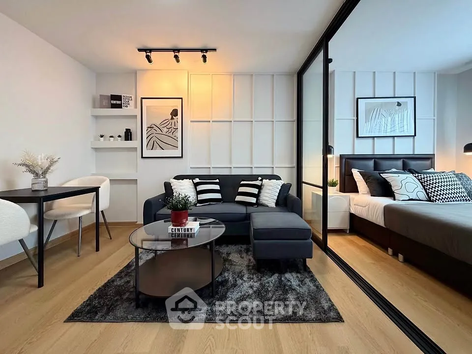 Modern living room with stylish decor and adjacent bedroom, featuring sleek furniture and elegant design.