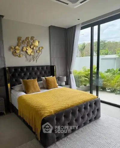 Luxurious bedroom with plush bed and garden view through large glass doors.
