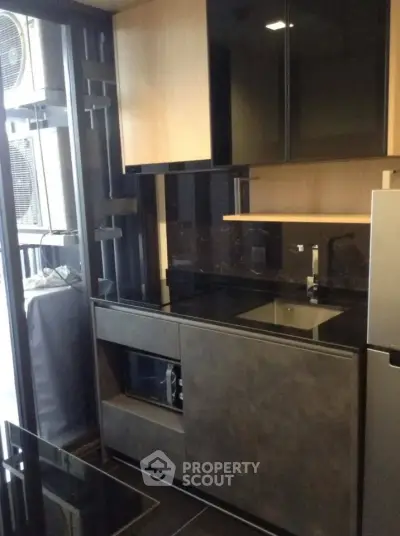 Modern compact kitchen with sleek black countertops and built-in appliances in a stylish apartment.