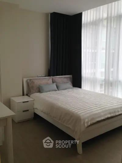 Modern bedroom with large windows and elegant curtains in a stylish apartment.