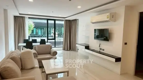Spacious modern living room with elegant furniture and large windows offering natural light.