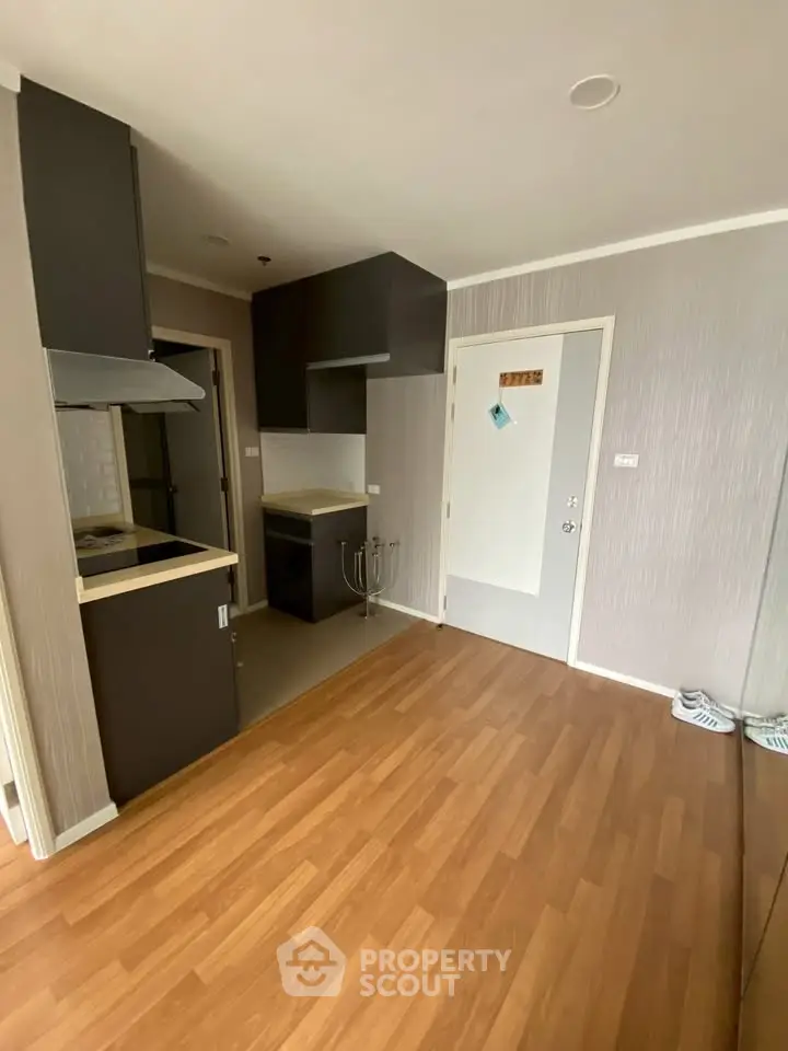 Modern compact kitchen with sleek cabinetry and wooden flooring in a cozy apartment.