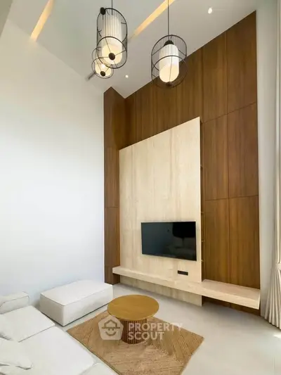 Modern living room with high ceiling, stylish lighting, and wooden accent wall featuring a mounted TV.
