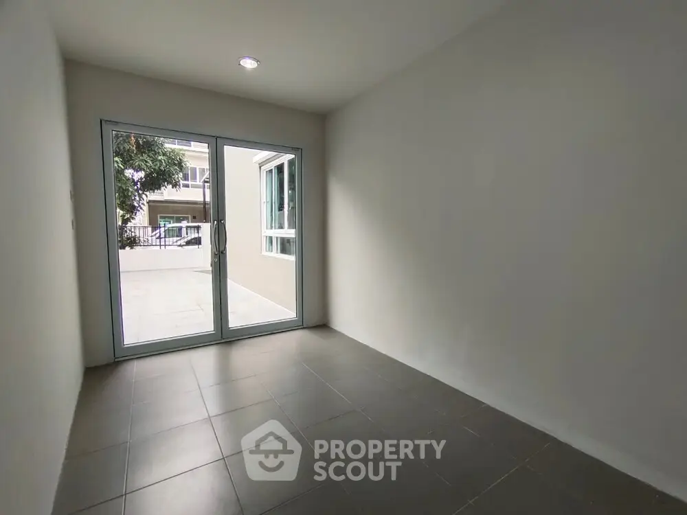 Spacious empty room with large glass doors leading to outdoor area, perfect for customization.