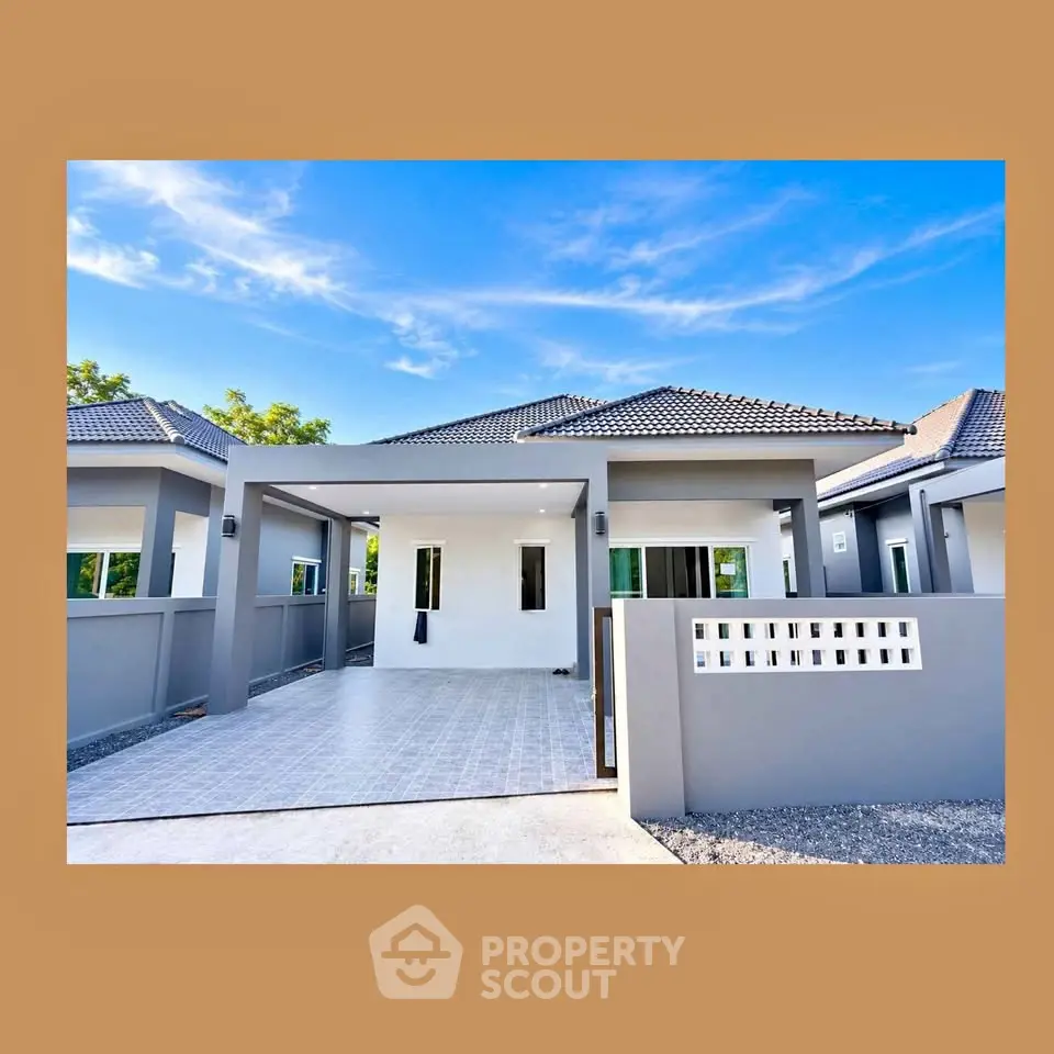 Modern single-story house with tiled roof and spacious driveway under clear blue sky.