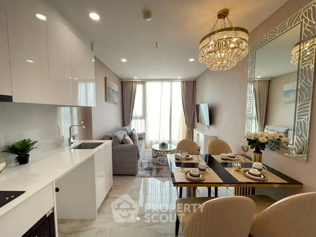 Luxurious open-plan living room and kitchen with elegant decor and chandelier lighting.