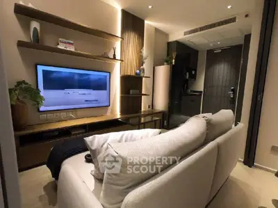 Modern living room with sleek design and cozy ambiance, featuring a wall-mounted TV and stylish shelving.